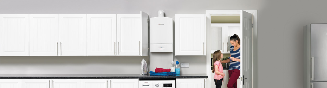 Photo of a woman in a kitchen adjusting a Worcester boiler.