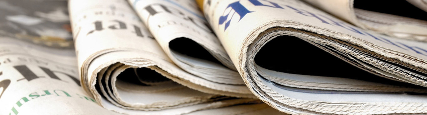 Closeup photo of newspapers stacked.