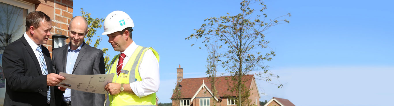 Photo of three men discussing a floorplan.